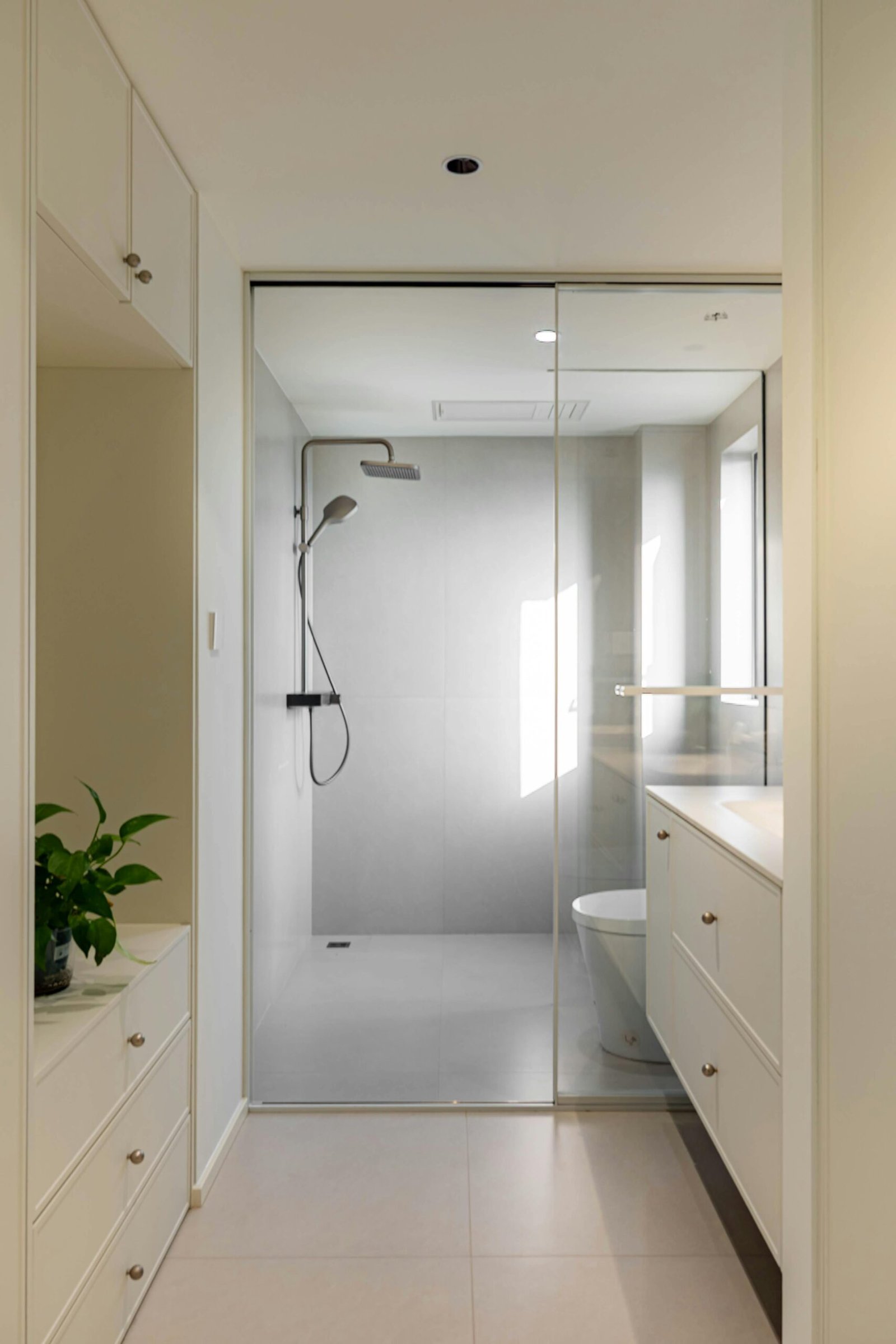 Bright and elegant modern bathroom with glass shower and sleek cabinetry.